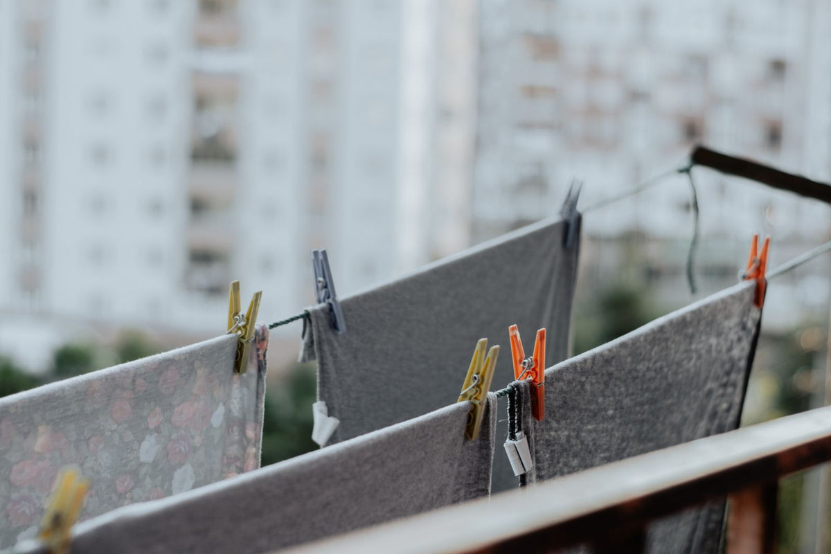 Grey laundry drying on a clothesline with clothespins