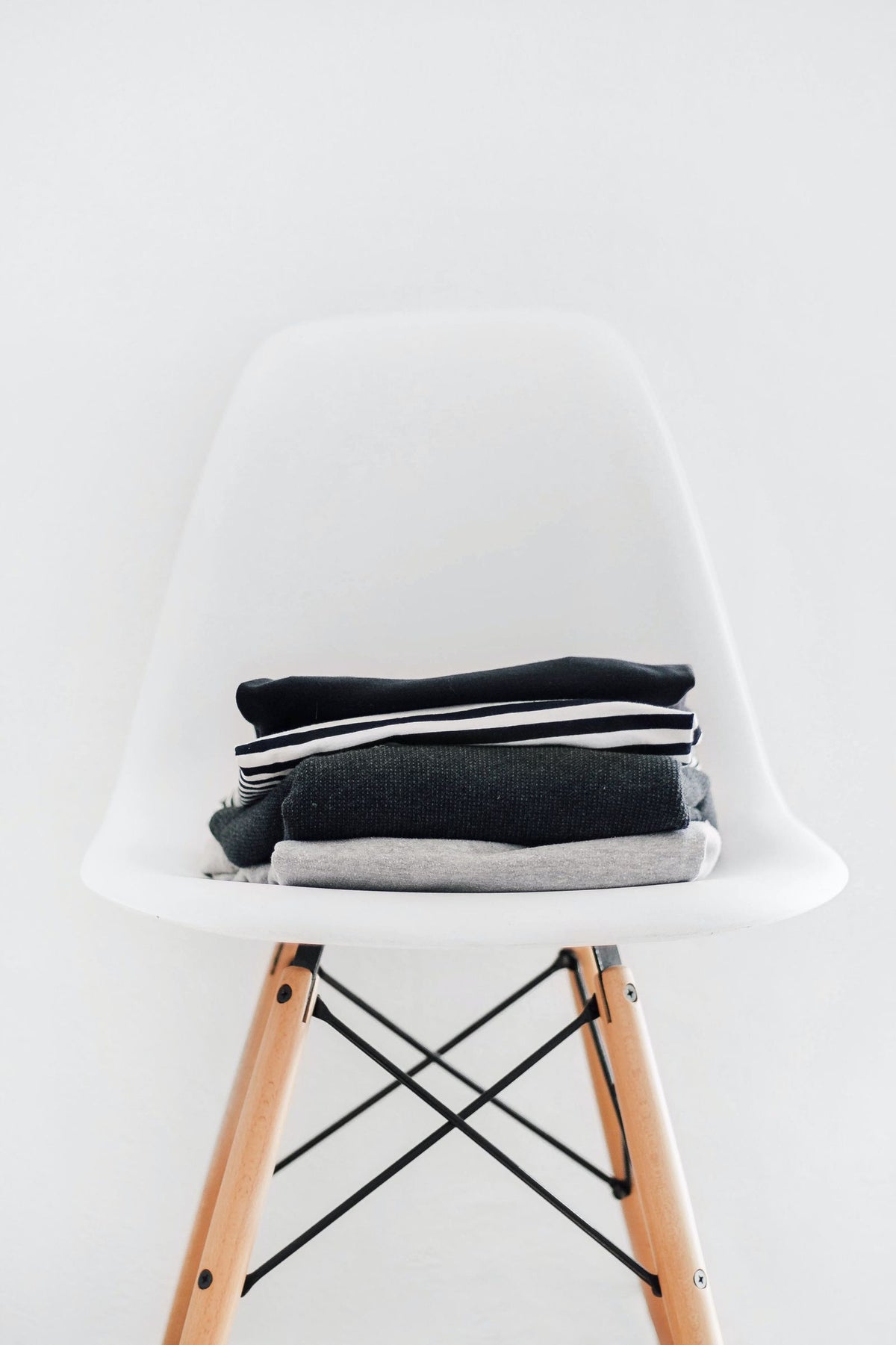 Neat stack of folded navy and charcoal men's basics on a white chair